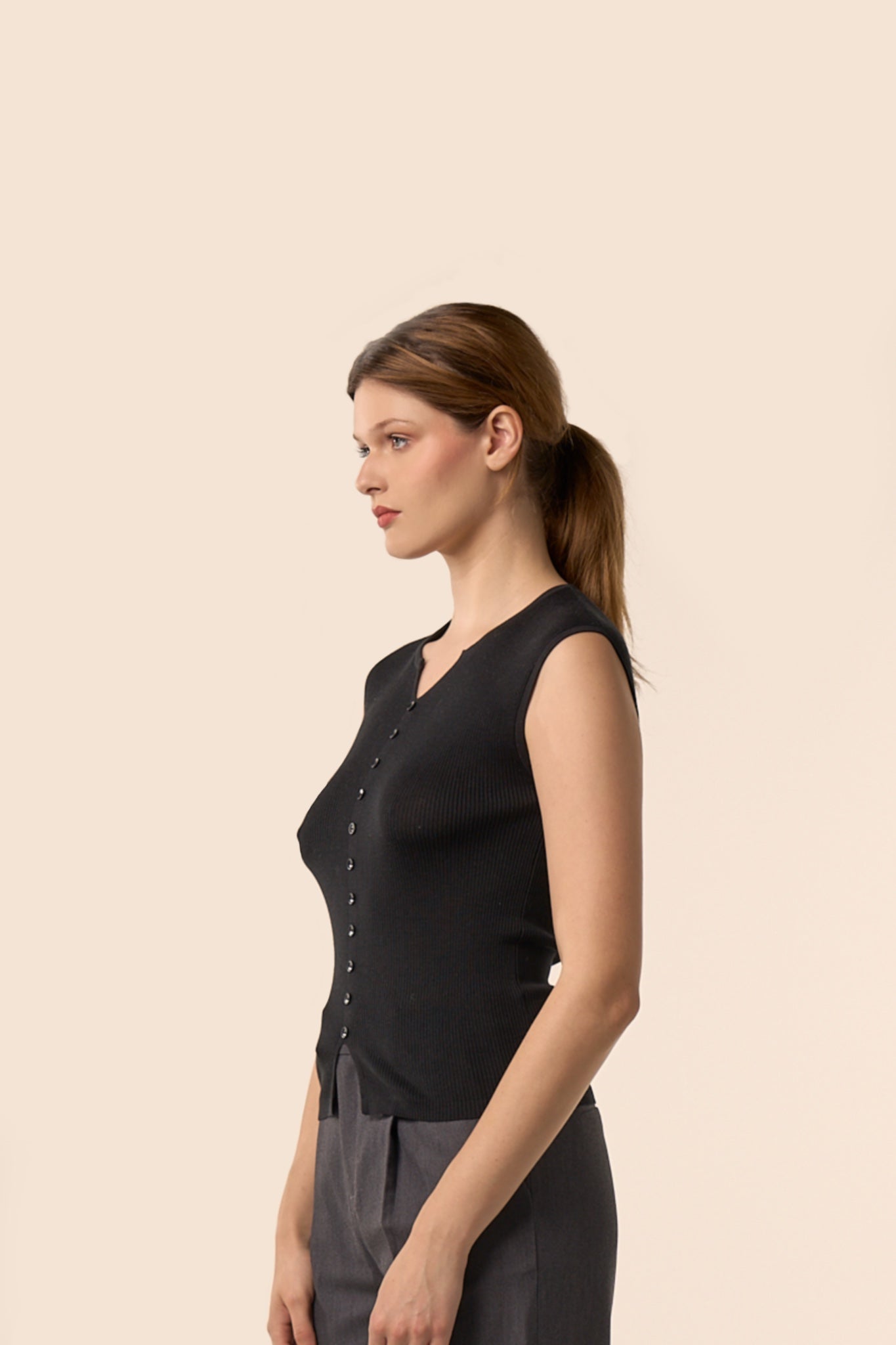 Top noir sans manches en maille côtelée, encolure légèrement ouverte et boutons ton sur ton, porté avec un pantalon gris anthracite — Pote aux Roses Paris