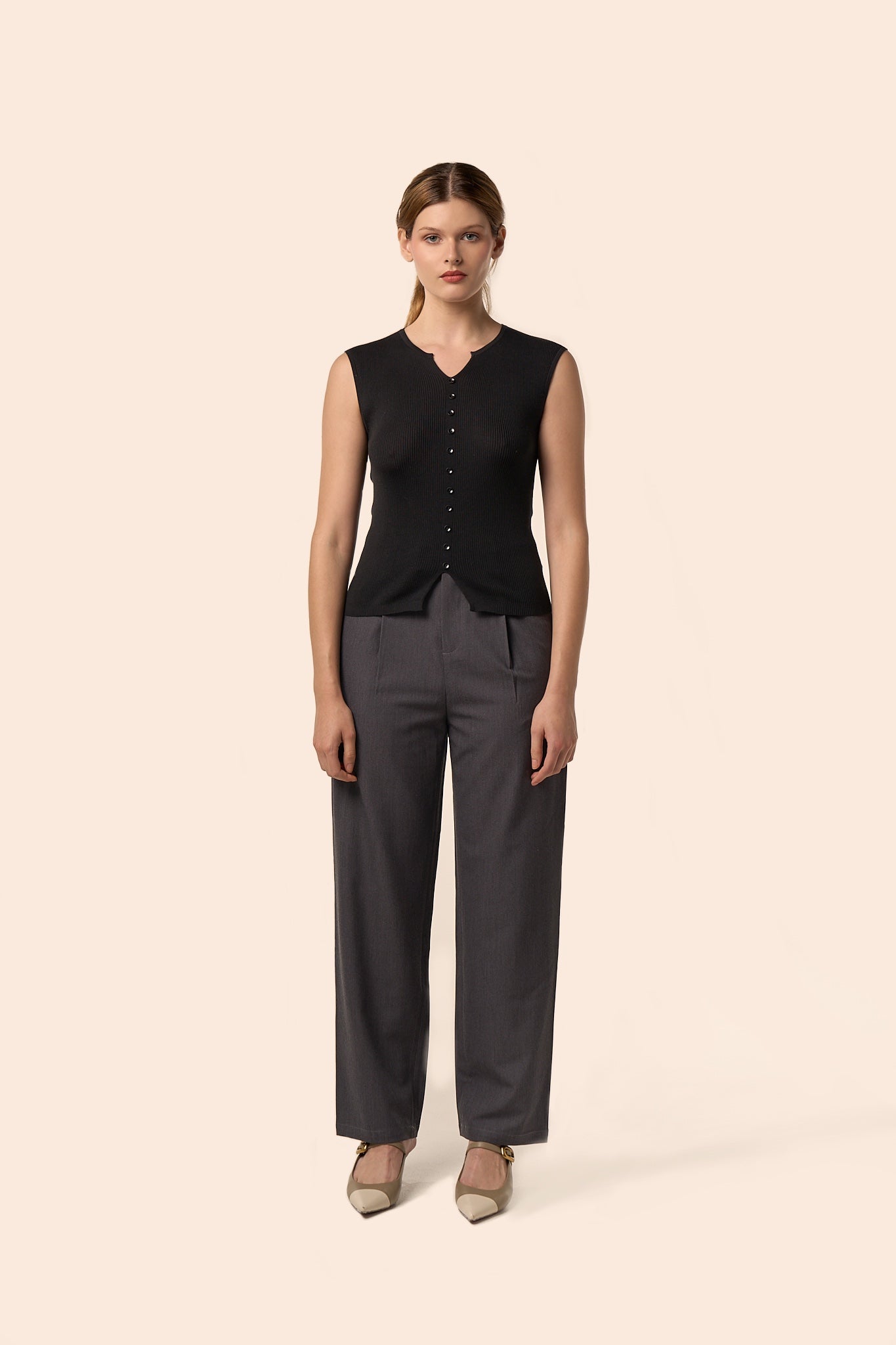 Top noir sans manches en maille côtelée, encolure légèrement ouverte et boutons ton sur ton, porté avec un pantalon gris anthracite — Pote aux Roses Paris