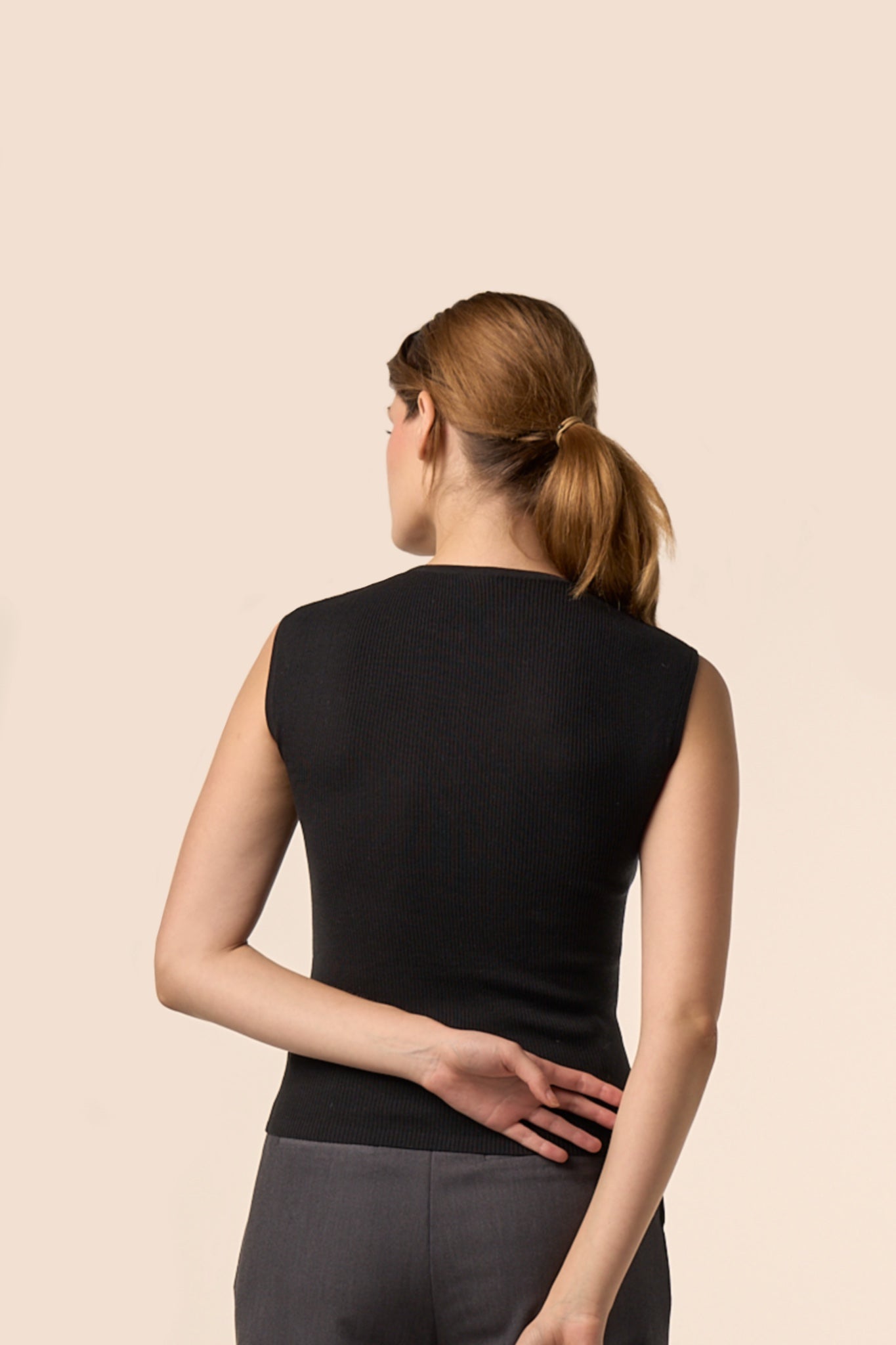 Dos du top noir sans manches en maille côtelée, coupe ajustée, porté avec un pantalon gris anthracite — Pote aux Roses Paris