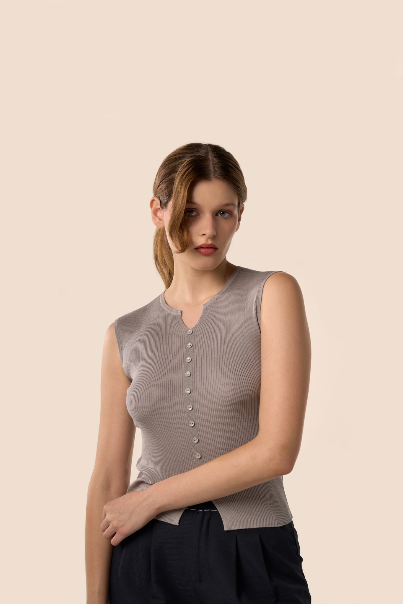 Top gris taupe sans manches en maille côtelée, encolure légèrement ouverte et boutons ton sur ton, porté avec un pantalon noir — Pote aux Roses Paris