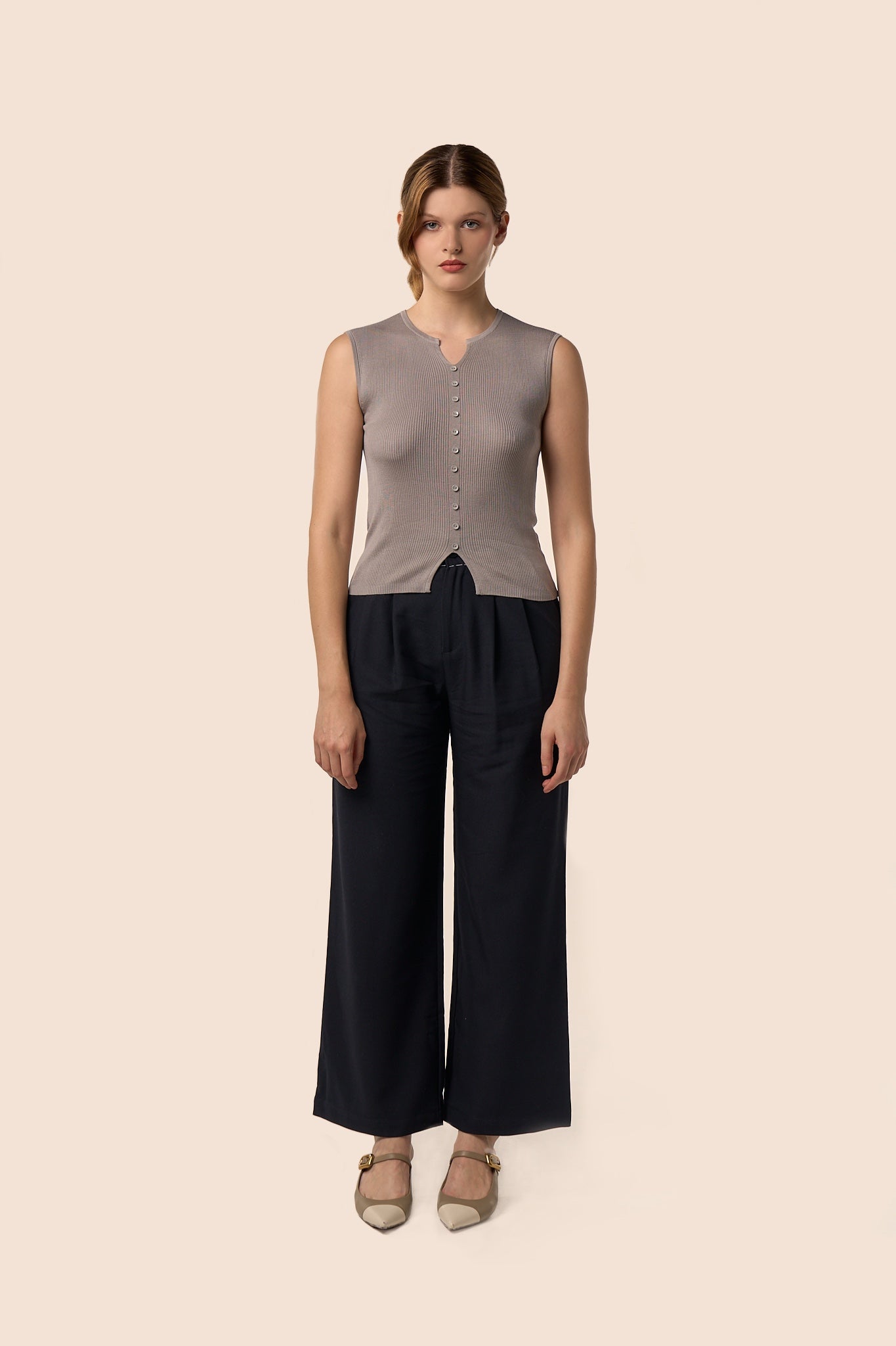 Top gris taupe sans manches en maille côtelée, encolure légèrement ouverte et boutons ton sur ton, porté avec un pantalon noir large — Pote aux Roses Paris