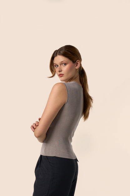 Top gris taupe sans manches en maille côtelée, coupe ajustée, vu de profil, porté avec un pantalon noir — Pote aux Roses Paris