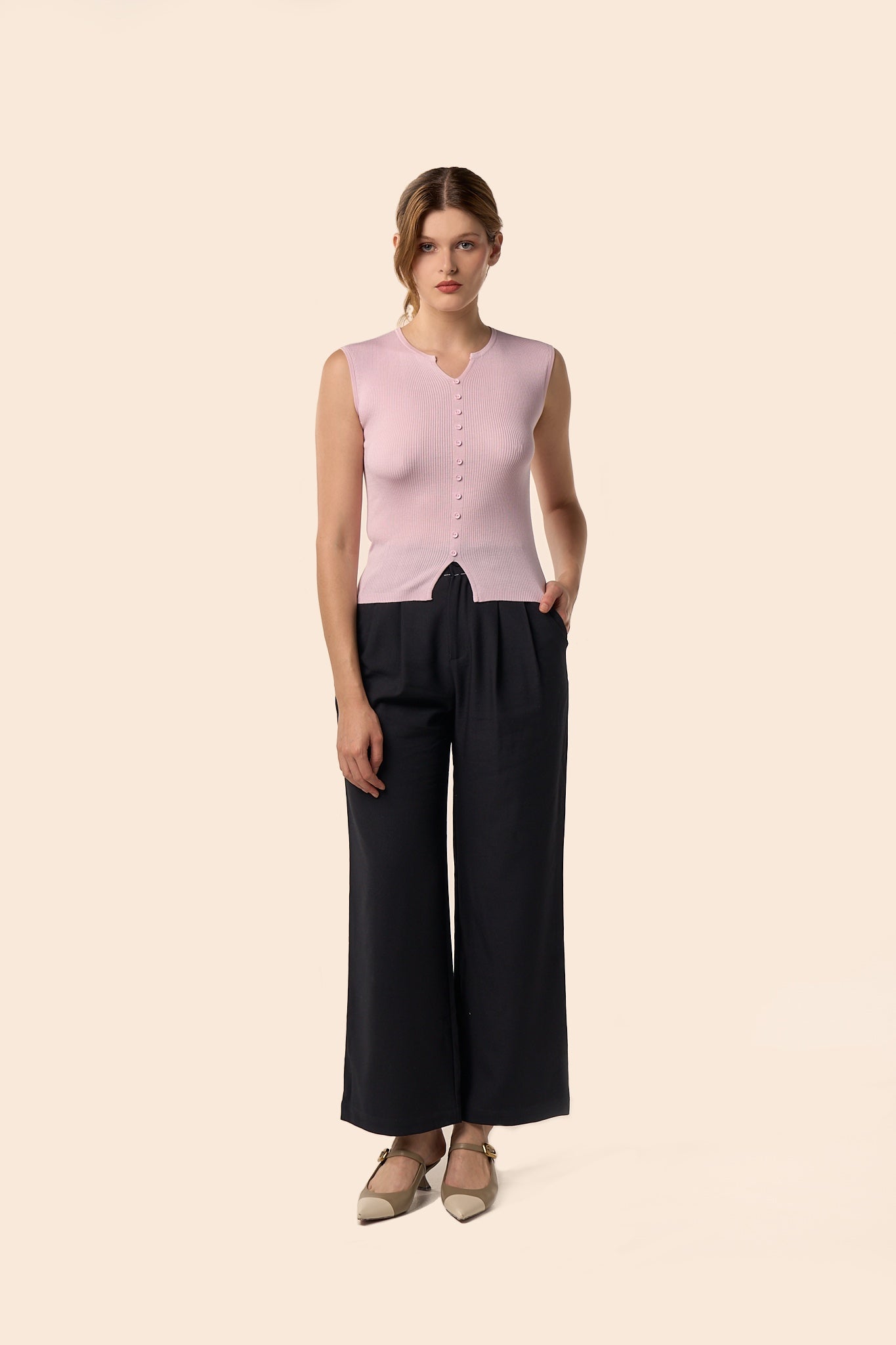 Top rose pâle sans manches en maille côtelée, encolure légèrement ouverte et boutons ton sur ton, porté avec un pantalon noir large — Pote aux Roses Paris