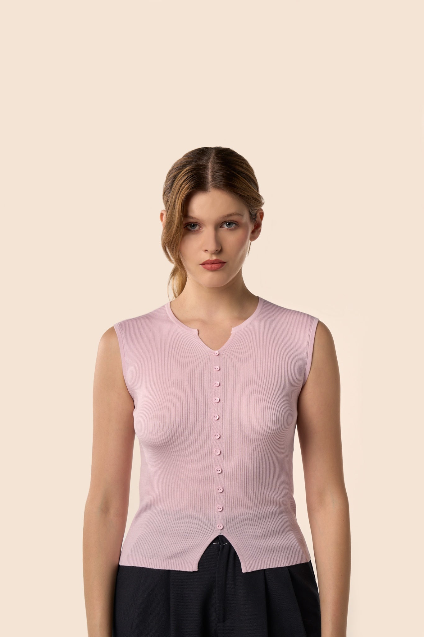 Top rose pâle sans manches en maille côtelée, encolure légèrement ouverte et boutons ton sur ton, porté avec un pantalon noir — Pote aux Roses Paris