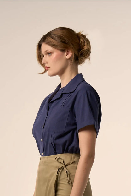 Chemise bleu marine à manches courtes, col classique et poche plaquée, portée avec une jupe portefeuille vert olive à lien noué — Pote aux Roses Paris