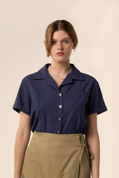 Chemise bleu marine à manches courtes, col classique et poche plaquée, portée avec une jupe portefeuille vert olive à lien noué — Pote aux Roses Paris