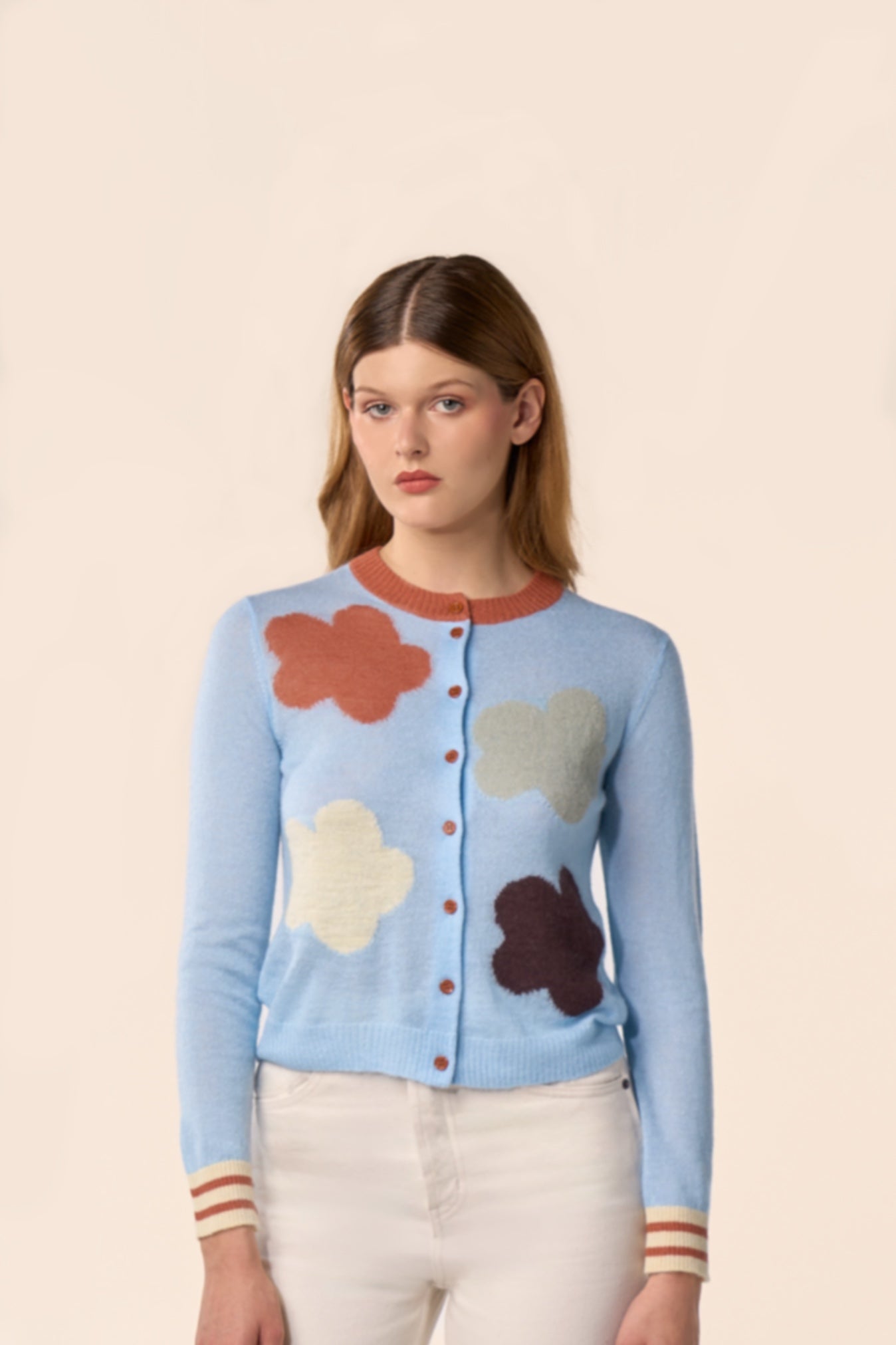 Cardigan bleu ciel en maille, manches longues, motifs nuages multicolores et poignets rayés, porté avec un pantalon écru — Pote aux Roses Paris