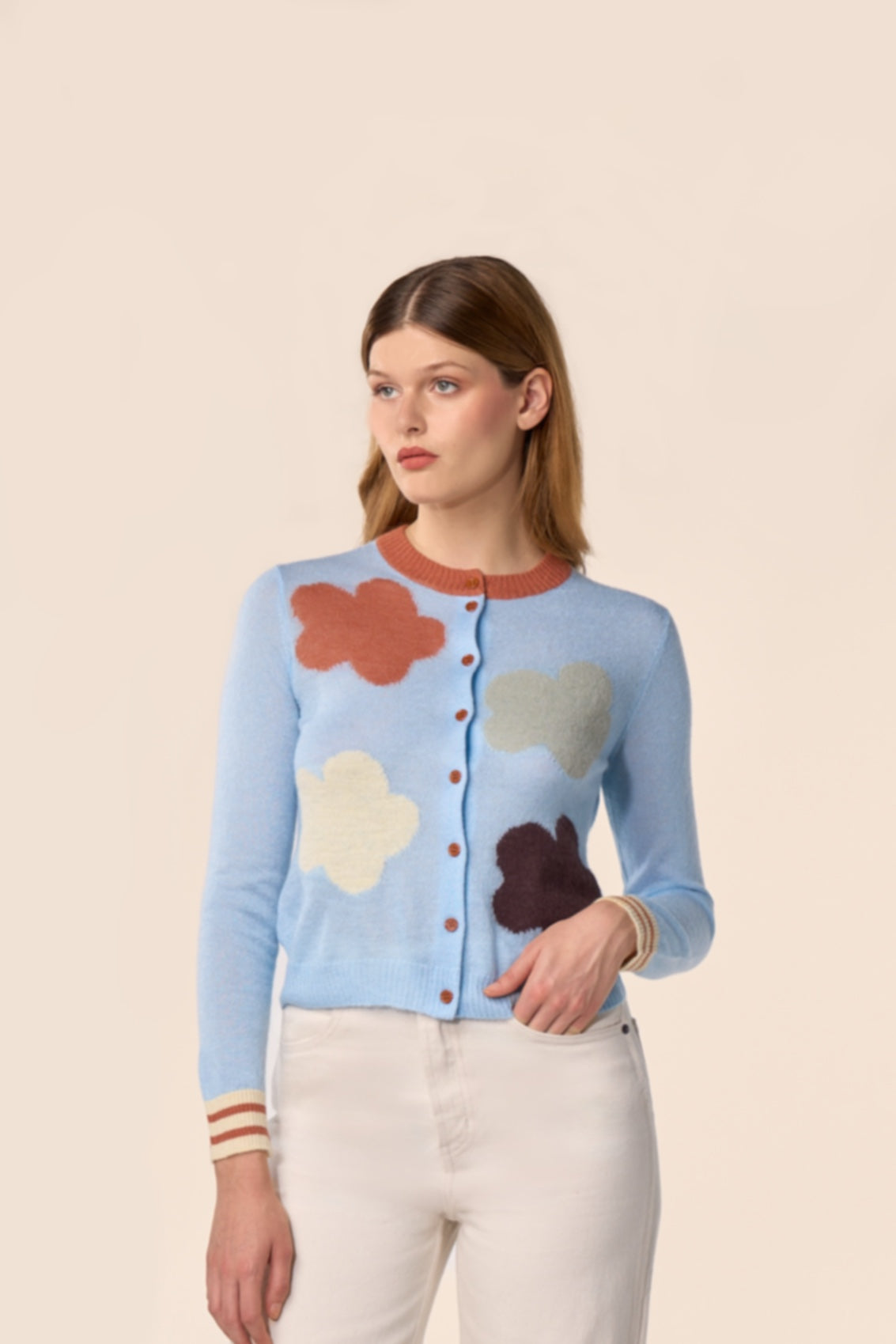 Cardigan bleu ciel en maille, manches longues, motifs nuages multicolores et poignets rayés, porté avec un pantalon écru — Pote aux Roses Paris