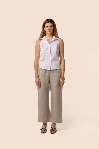 Chemise blanche sans manches à col classique, coupe ajustée et poche plaquée, portée avec un pantalon beige en lin mélangé — Pote aux Roses Paris