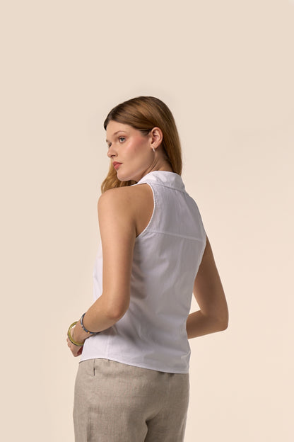 Chemise blanche sans manches à col classique, dos légèrement ajusté et empiècement, portée avec un pantalon beige en lin mélangé — Pote aux Roses Paris