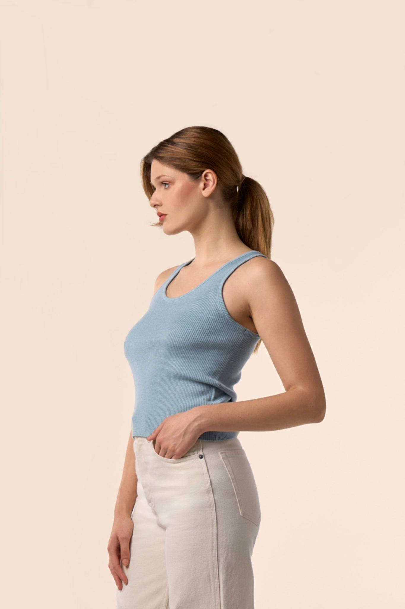 Top sans manches bleu ciel en maille côtelée à encolure ronde, vu de profil, porté avec un pantalon blanc - Pote aux Roses Paris
