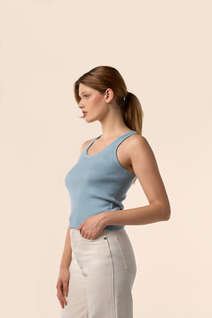Top sans manches bleu ciel en maille côtelée à encolure ronde, vu de profil, porté avec un pantalon blanc - Pote aux Roses Paris